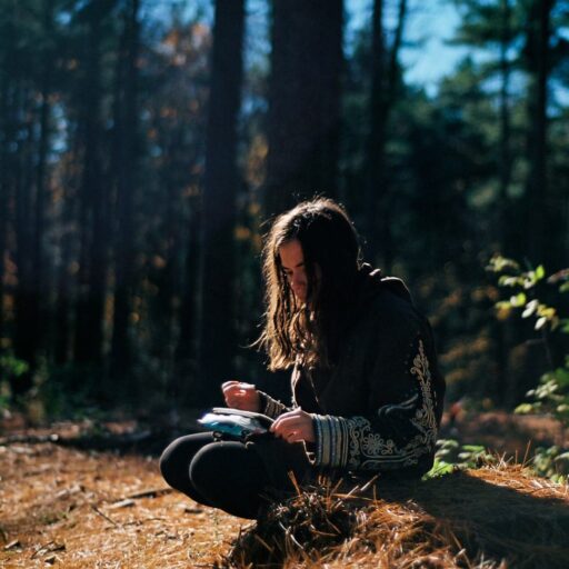 a woman sitting on a log in the woods